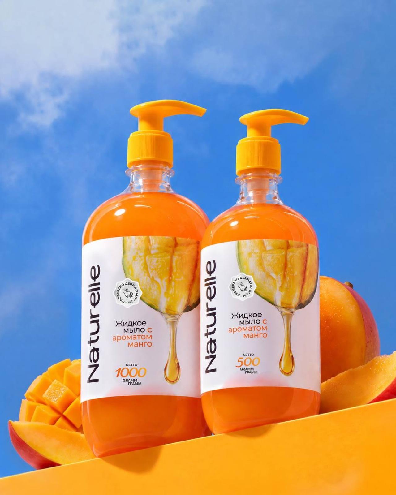 Naturelle mango hand soap — two bottles against a blue sky with fresh mangoes
